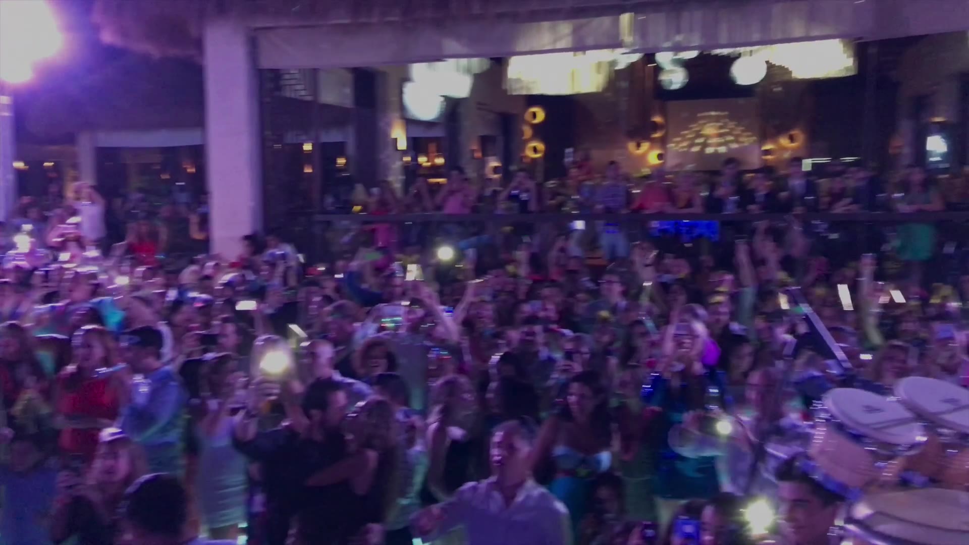 A packed open-air terrace at night — the first frame of the reel